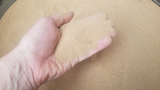 Hand holding tan mealworm frass powder