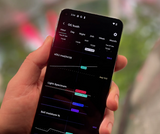 Hand holding a smartphone displaying real-time environmental metrics like eDLI, light spectrum, and soil moisture % in the Grow Sensor PRO mobile app dashboard.