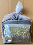 Mesh brew bag of dark compost with a bag of dry tea ingredients in front