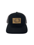 Black snapback trucker hat with gray mesh back and a leather KiS Organics patch